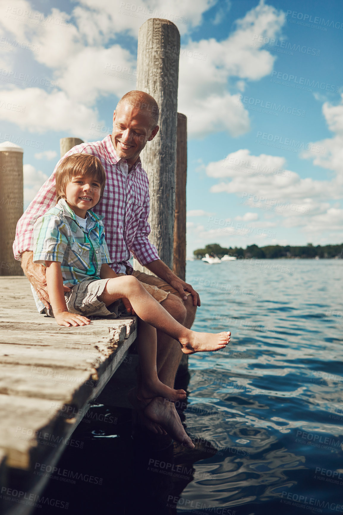 Buy stock photo Shot of a young father and son on a pier while out by the lake