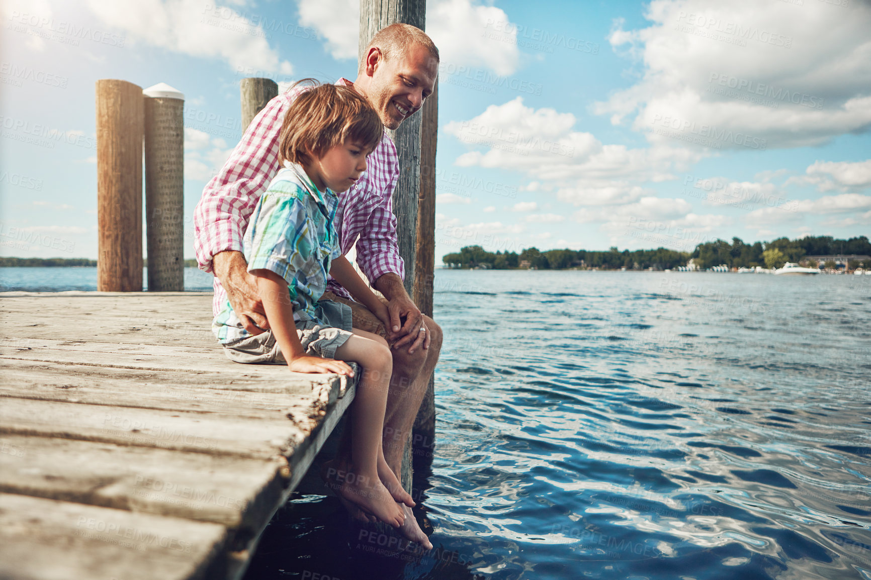 Buy stock photo Shot of a young father and son on a pier while out by the lake