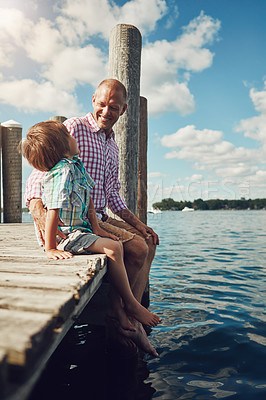 Buy stock photo Shot of a young father and son on a pier while out by the lake