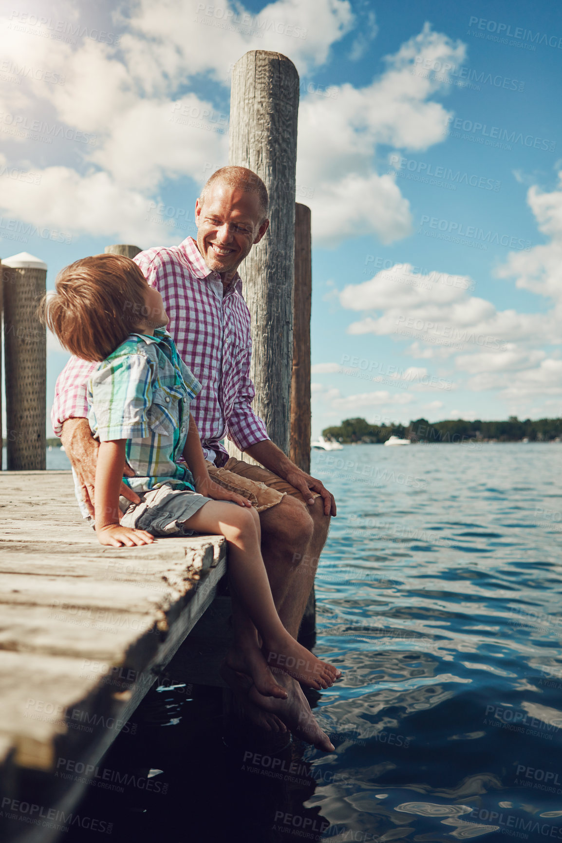 Buy stock photo Shot of a young father and son on a pier while out by the lake