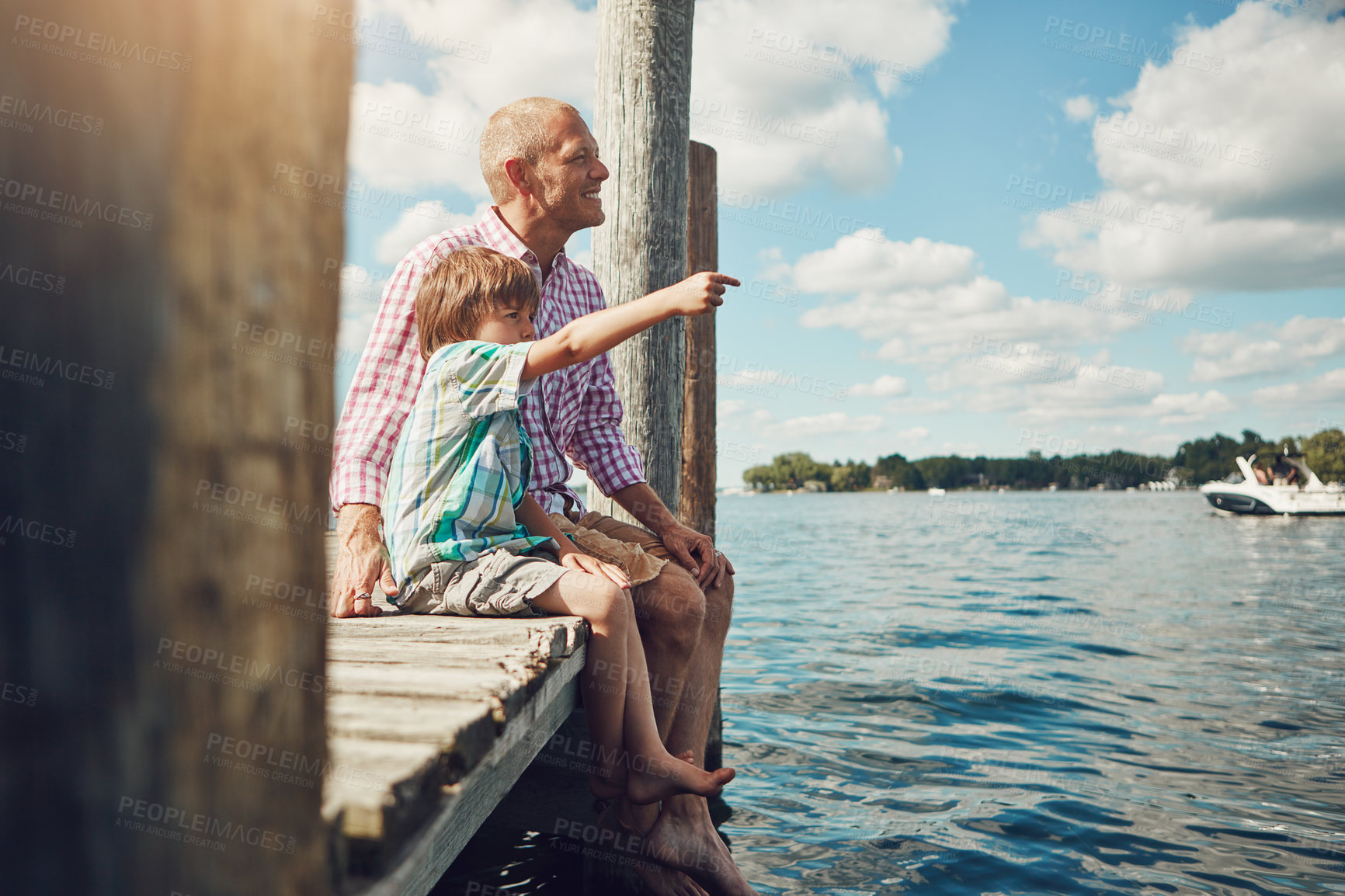 Buy stock photo Shot of a young father and son on a pier while out by the lake