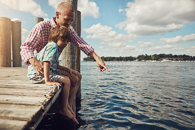 Buy stock photo Shot of a young father and son on a pier while out by the lake