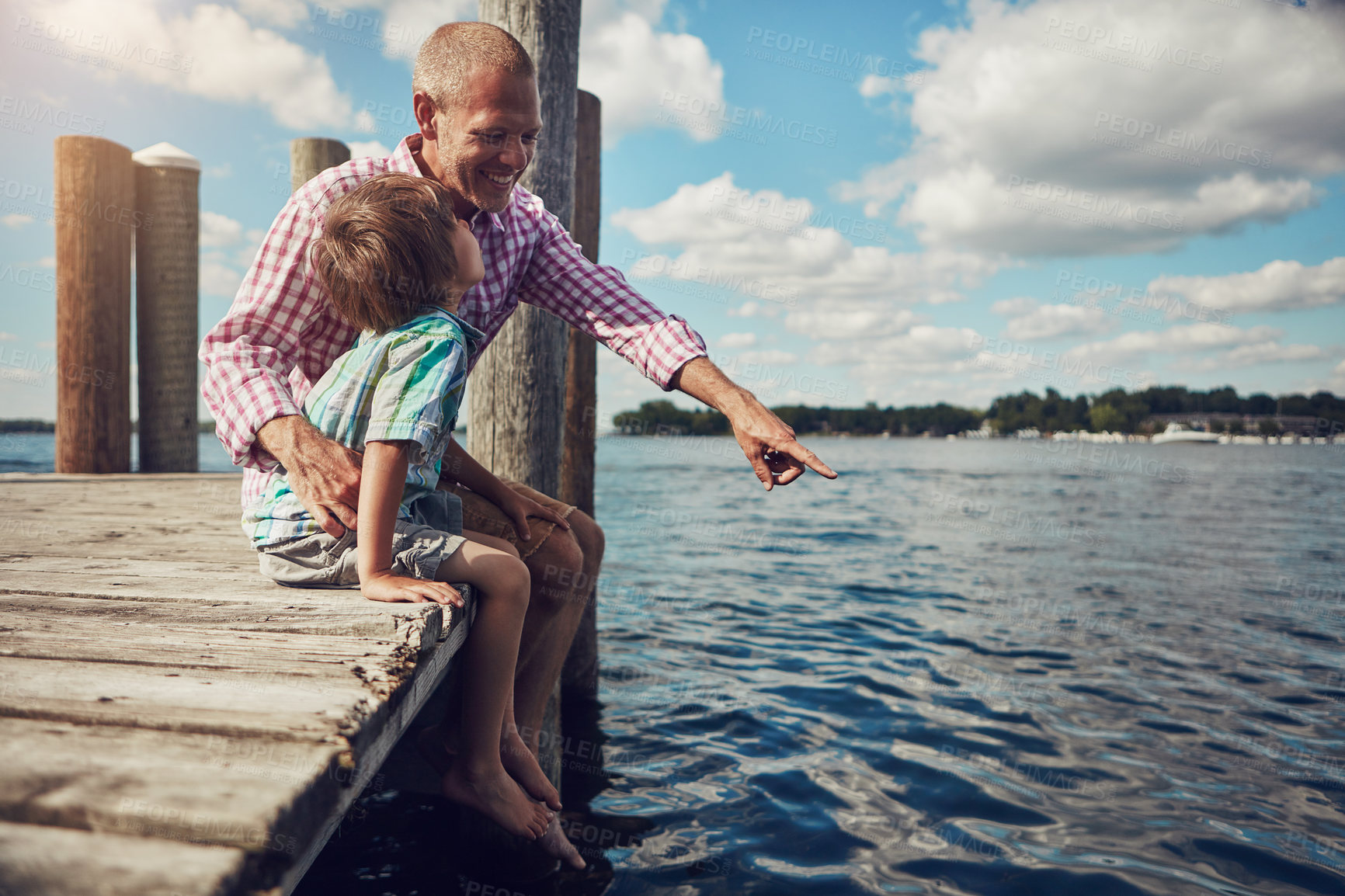 Buy stock photo Shot of a young father and son on a pier while out by the lake