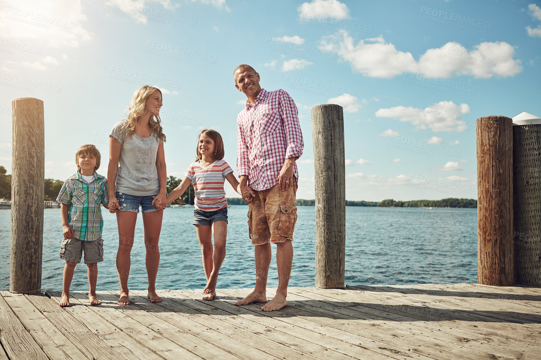 Buy stock photo Shot of a young family on a pier while out by the lake