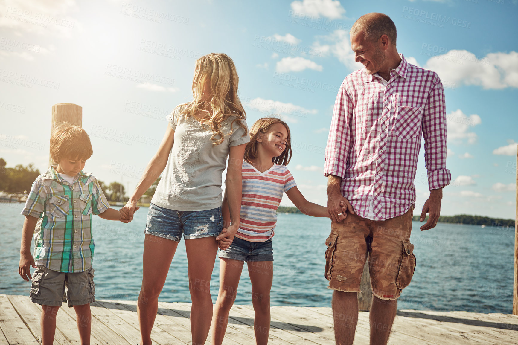 Buy stock photo Shot of a young family on a pier while out by the lake