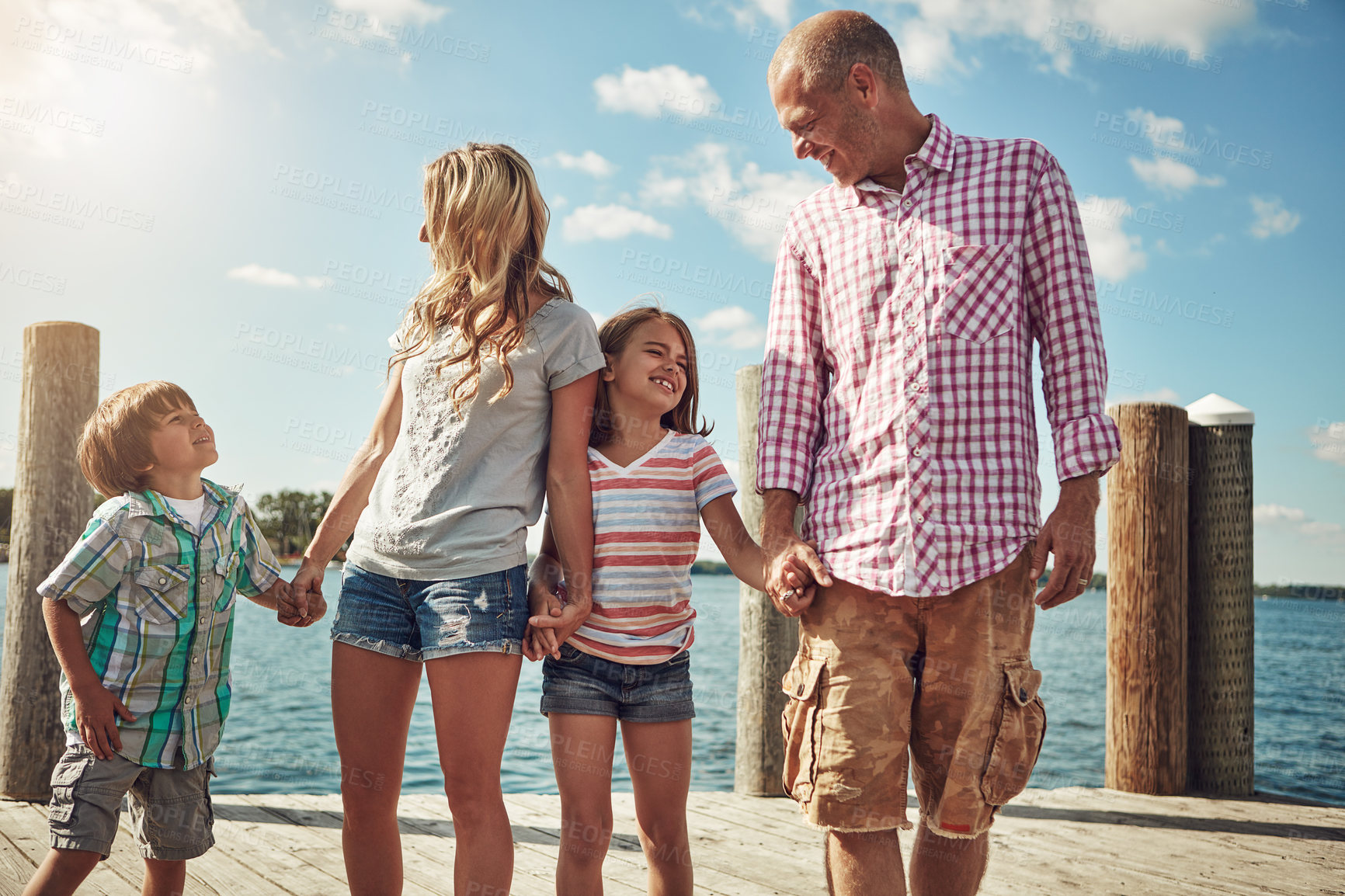 Buy stock photo Shot of a young family on a pier while out by the lake