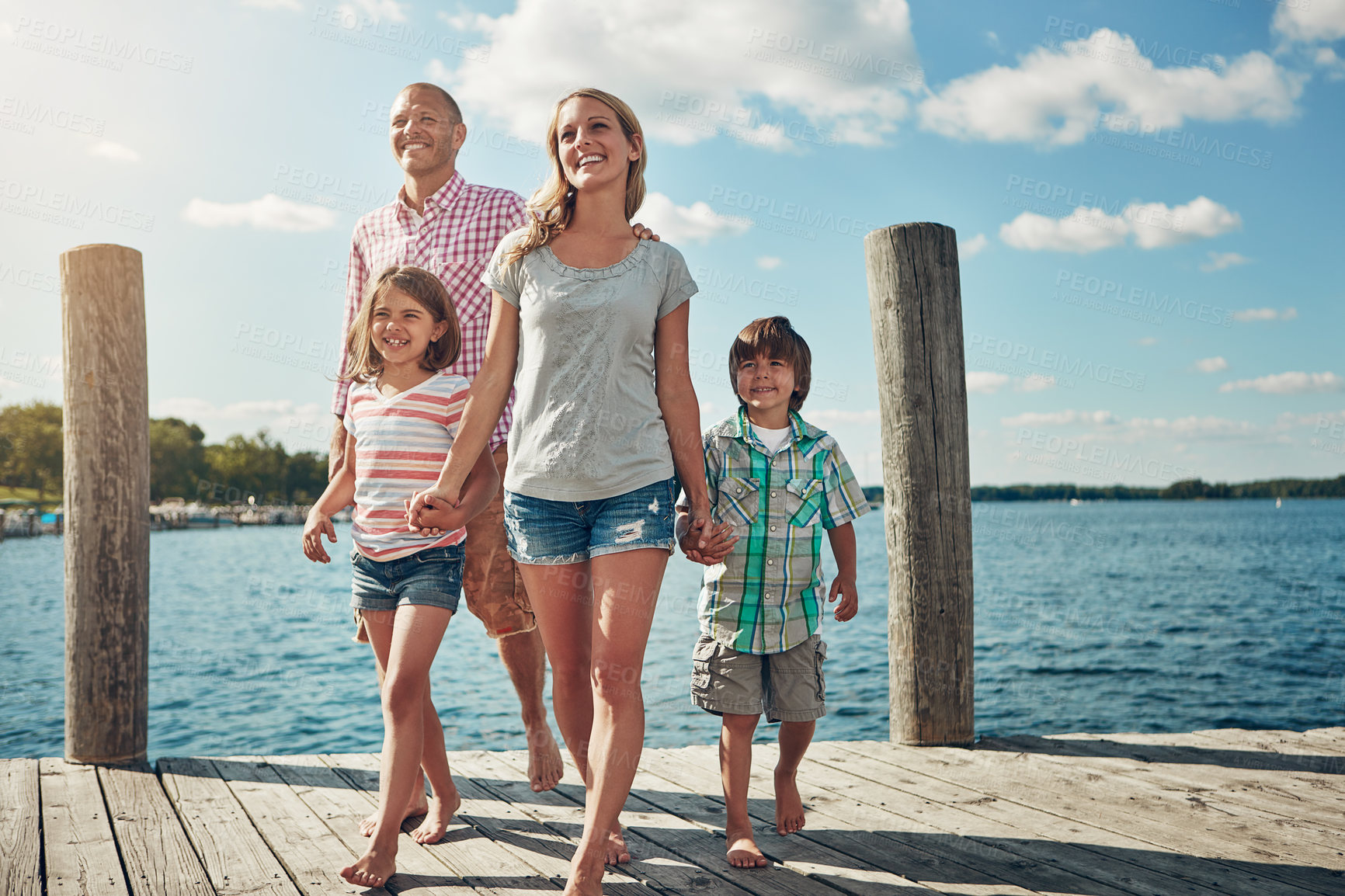 Buy stock photo Shot of a young family on a pier while out by the lake