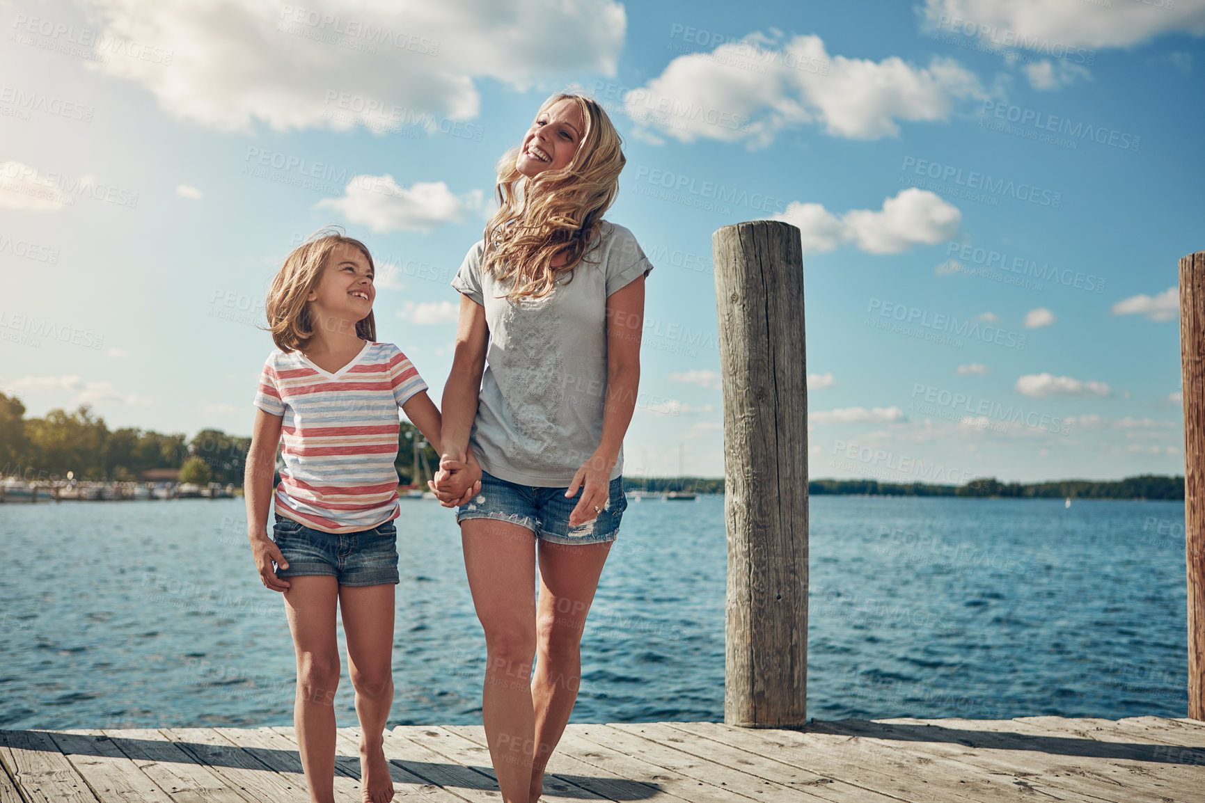 Buy stock photo Shot of a young mother and daughter on a pier while out by the lake