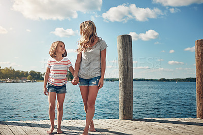 Buy stock photo Shot of a young mother and daughter on a pier while out by the lake