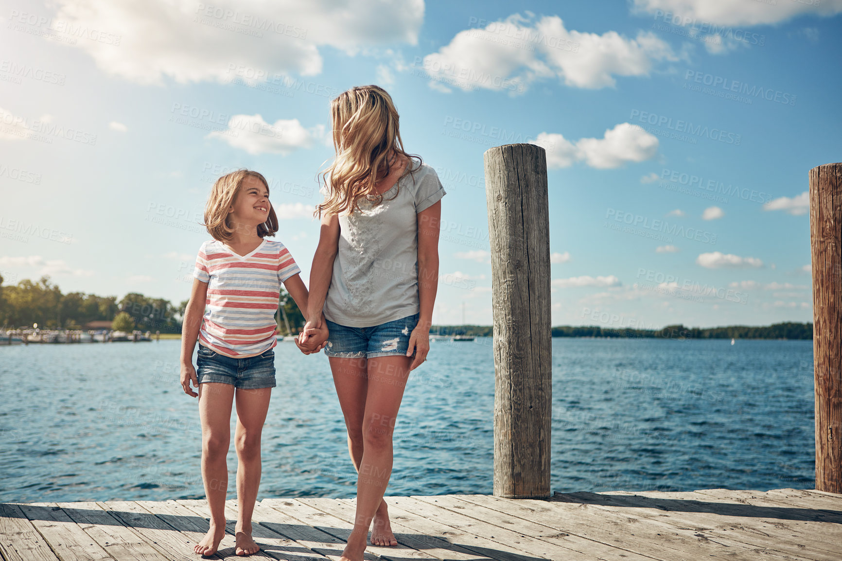 Buy stock photo Shot of a young mother and daughter on a pier while out by the lake