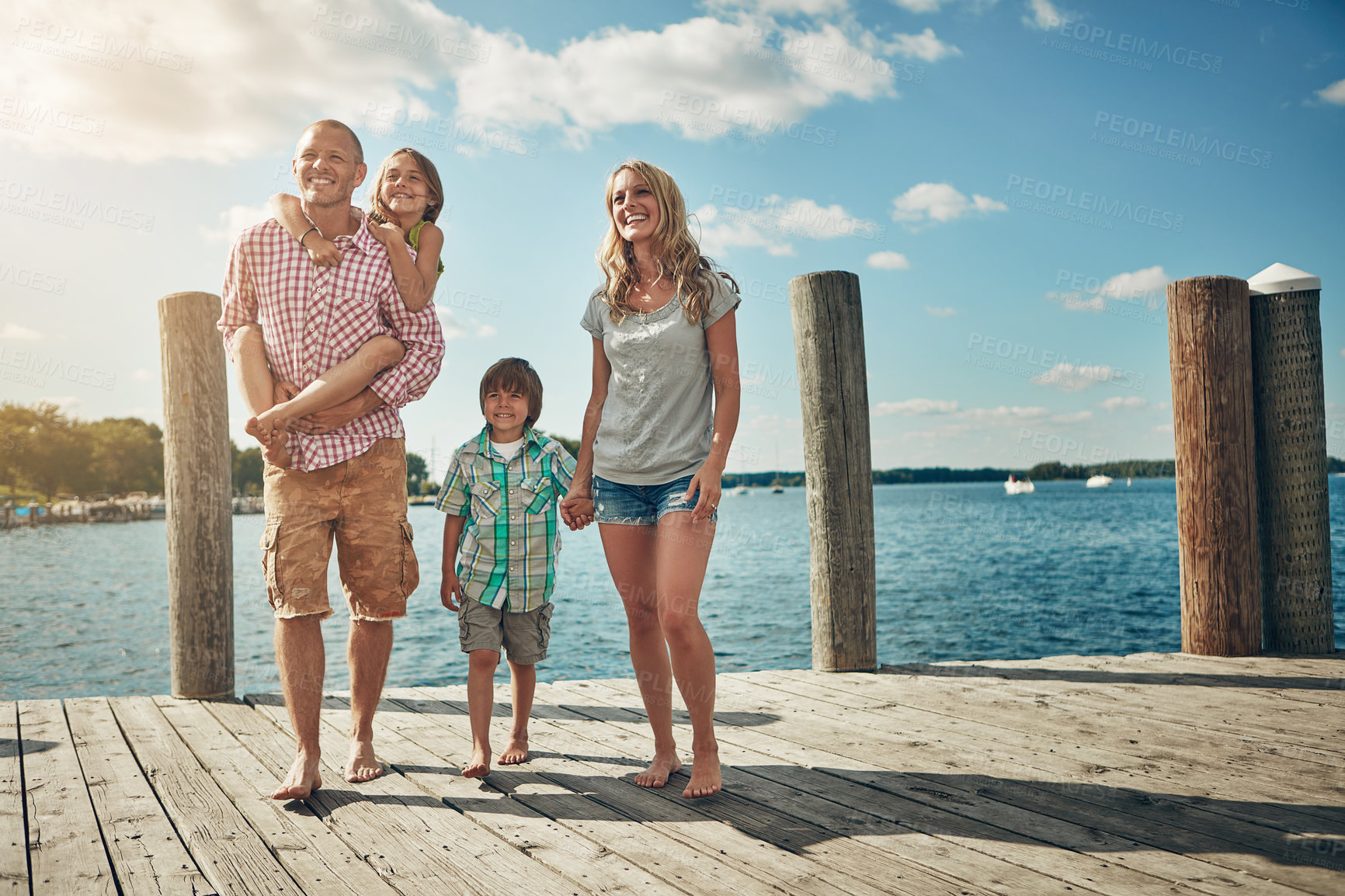 Buy stock photo Shot of a young family on a pier while out by the lake