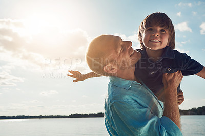 Buy stock photo Shot of a middle-aged man and his young son spending some quality time at the beach