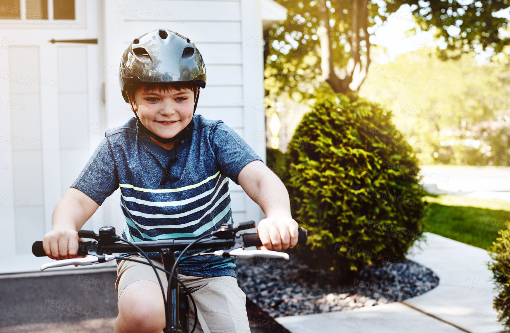 Buy stock photo Shot of a young boy riding his bicycle through his neighbourhood