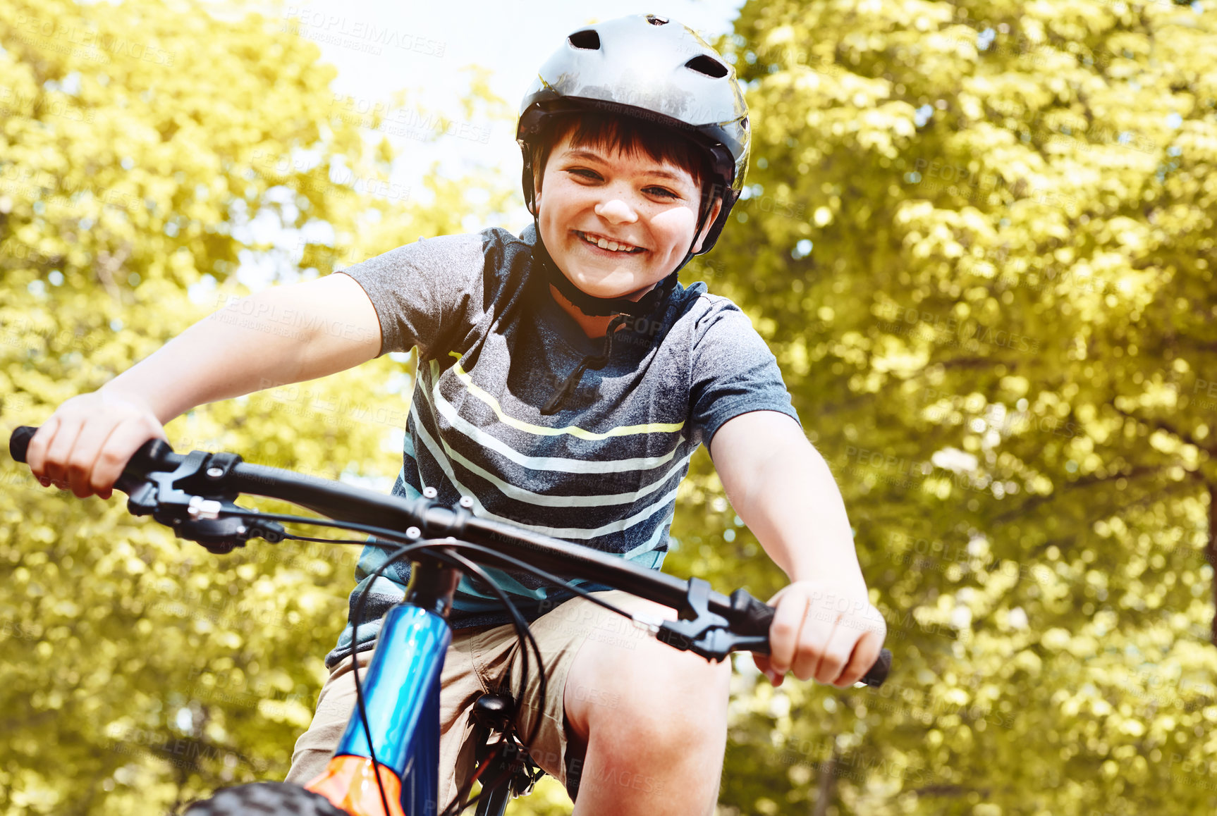 Buy stock photo Shot of a young boy riding his bicycle through his neighbourhood