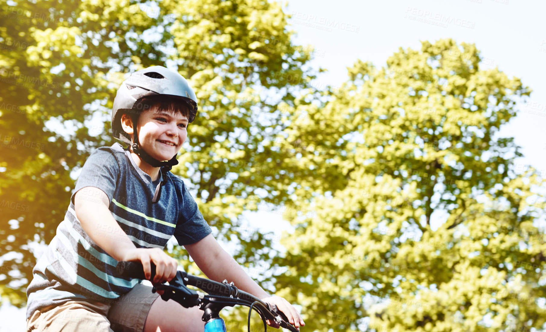 Buy stock photo Shot of a young boy riding his bicycle through his neighbourhood