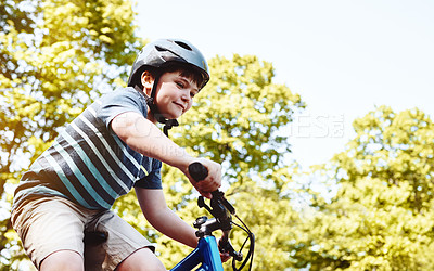 Buy stock photo Shot of a young boy riding his bicycle through his neighbourhood