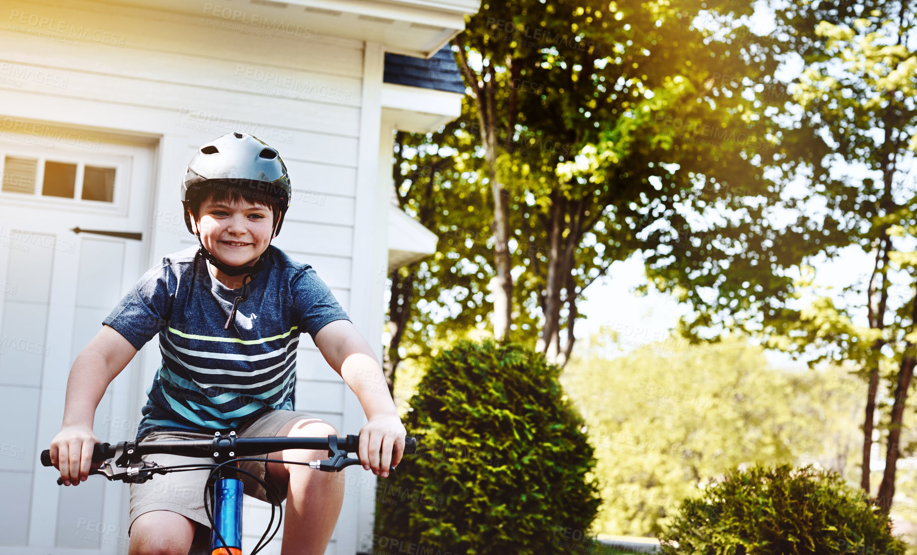 Buy stock photo Shot of a young boy riding his bicycle through his neighbourhood