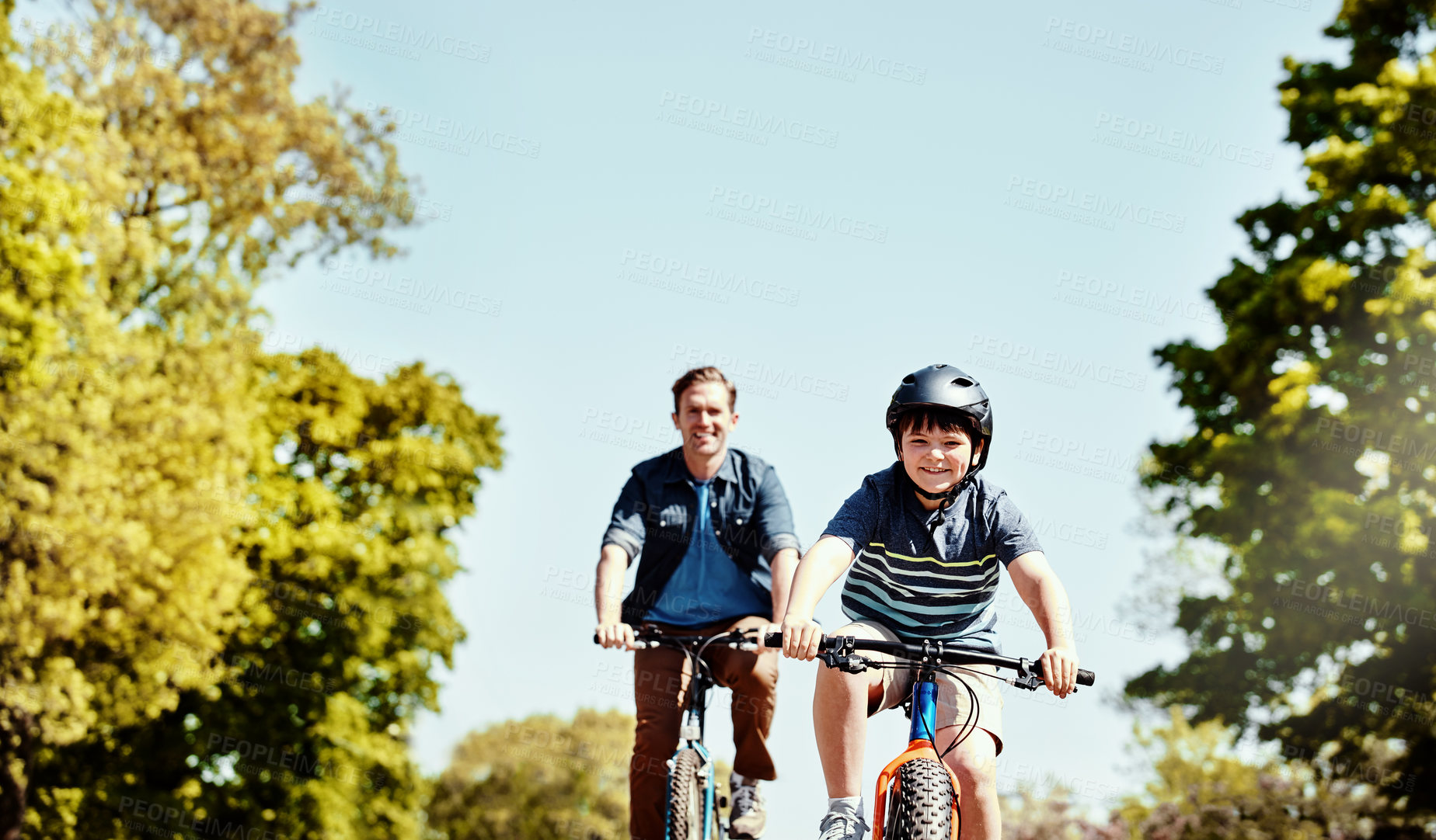 Buy stock photo Shot of a young boy and his father riding together on their bicycles