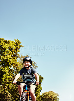 Buy stock photo Shot of a young boy riding his bicycle through his neighbourhood