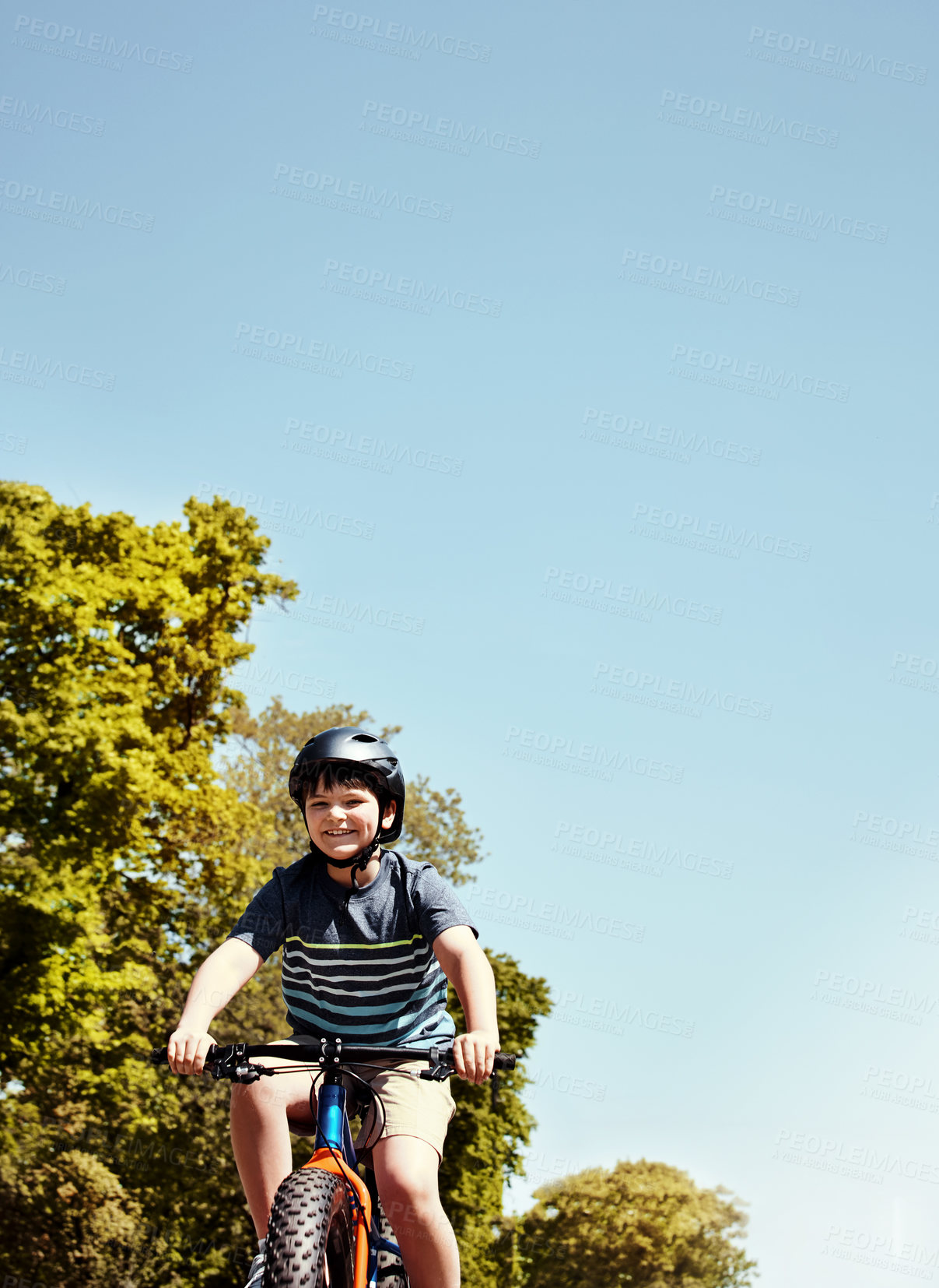 Buy stock photo Shot of a young boy riding his bicycle through his neighbourhood