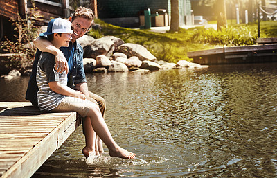 Buy stock photo Shot of a father and his little son sitting on a pier at a lake