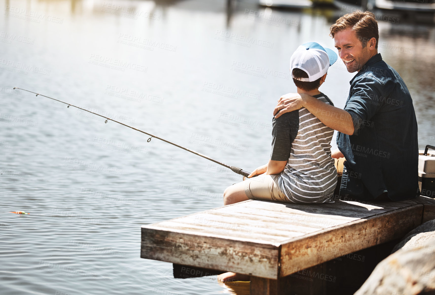 Buy stock photo Happy father, teaching son and fishing with rod by lake, ocean or beach together in nature. Dad with child, young kid or little boy with hug for bonding lesson or tips to catch sea creatures by water