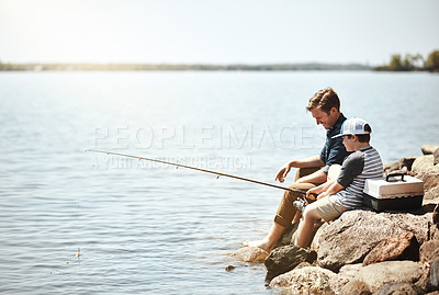 Buy stock photo Happy father, son and fishing on rock with rod by lake, ocean or beach together in nature. Dad with child, young kid or little boy with smile for bonding, lesson or teaching tip to catch by sea water