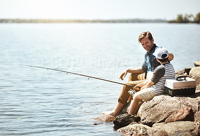 Buy stock photo Happy dad, son and fishing on rock with rod by lake, ocean or beach together in nature. Father with child, young kid or little boy with smile for bonding, lesson or teaching tip to catch by sea water