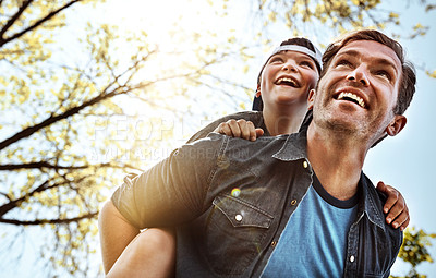 Buy stock photo Low angle shot of a father giving his little son a piggyback ride outdoors