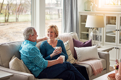 Buy stock photo Senior couple, coffee and happy on sofa in conversation, relax and memory in home living room. Old man, elderly woman and smile for bonding with care, love and story in retirement on couch in house