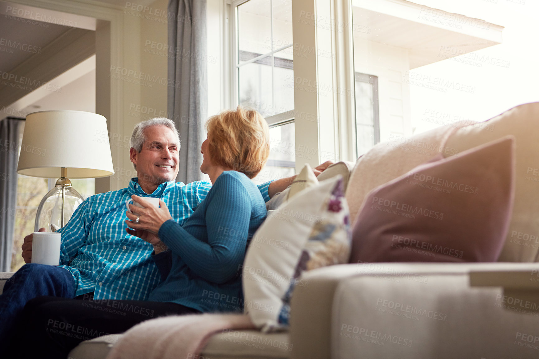 Buy stock photo Senior couple, tea and smile on couch in conversation, relax or happy memory in home living room. Old man, elderly woman and chat for bonding with coffee, love or story in retirement on sofa in house