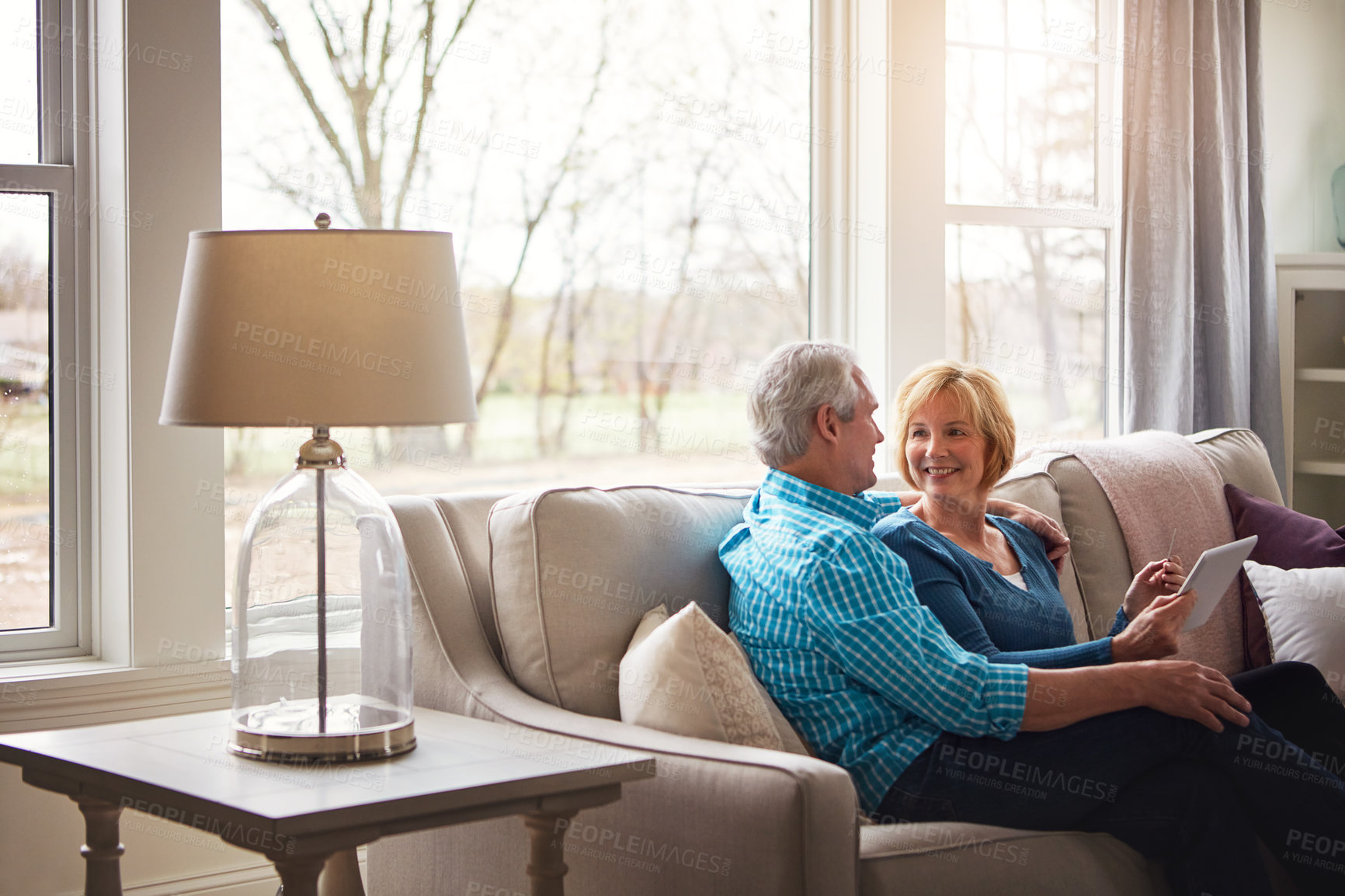 Buy stock photo Shot of a happy mature couple relaxing on the sofa and using a digital tablet and credit card together