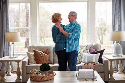 Buy stock photo Shot of a happy mature couple dancing together in their living room at home