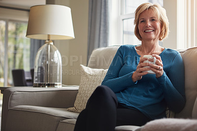 Buy stock photo Shot of a happy mature woman relaxing on the sofa with a warm beverage at home