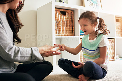 Buy stock photo Shot of a little girl playing rock, paper, scissors with her mother at home