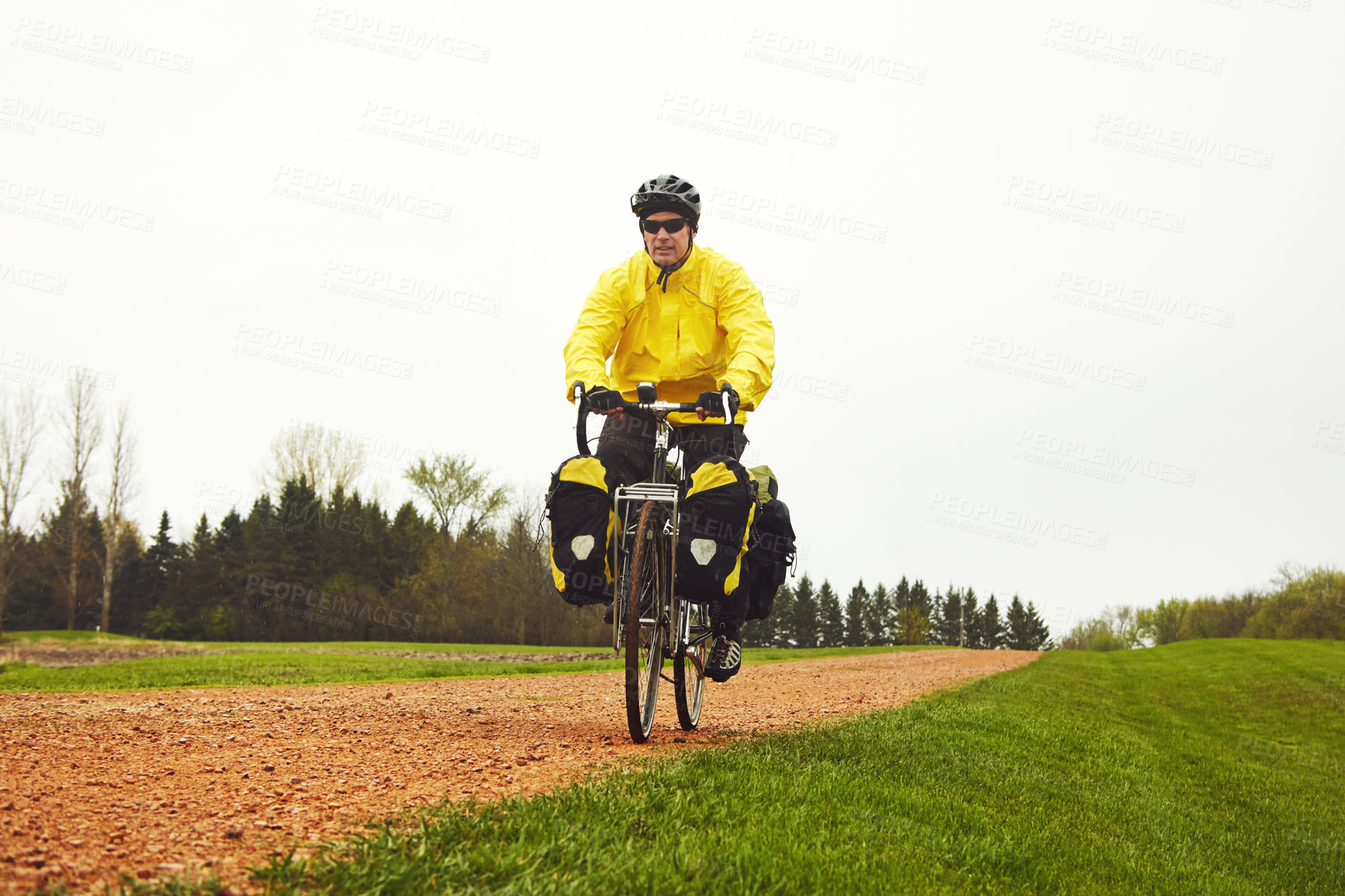 Buy stock photo Full length shot of a male cyclist enjoying a bike ride on a wet winter's morning