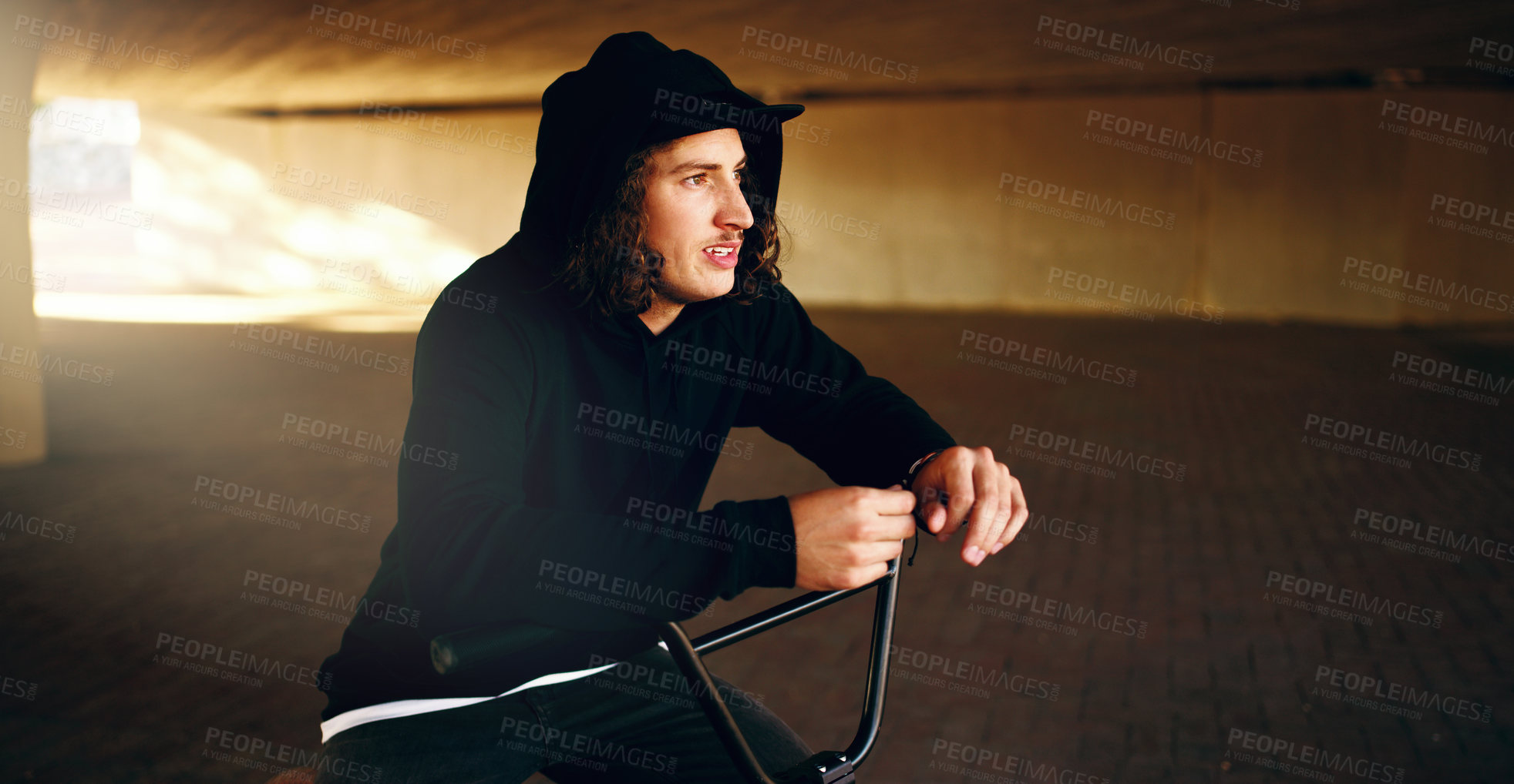 Buy stock photo Cropped shot of a young man chilling on his BMX in an underground parking lot