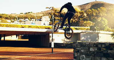 Buy stock photo Full length shot of a young male BMX rider doing tricks around the city