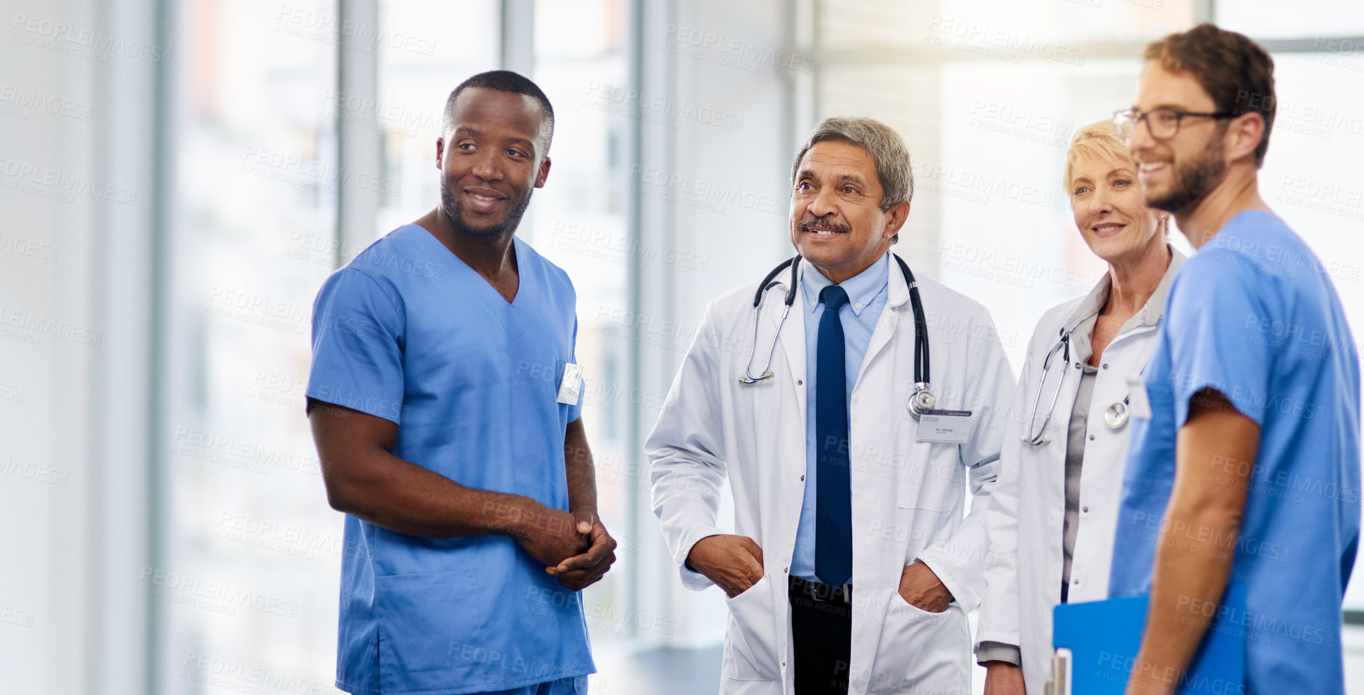 Buy stock photo Team of happy doctors having a group discussion about professional healthcare together in a hospital. Friendly young and mature medical workers standing together smiling after a successful treatment