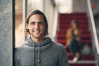 Buy stock photo Cropped portrait of a handsome young university student standing in a hallway on campus