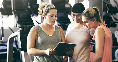 Buy stock photo Cropped shot of three sporty young women looking at a digital tablet in the gym