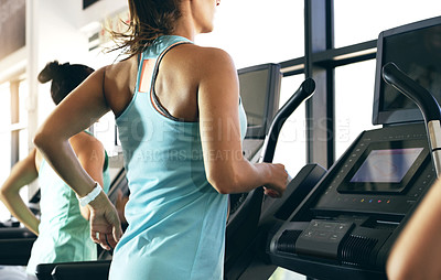 Buy stock photo Rearview shot of two unrecognizable young women working out on treadmills in the gym