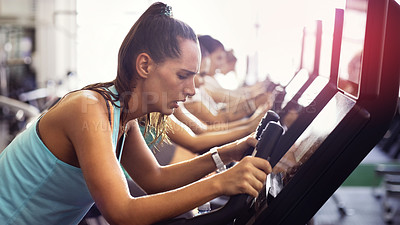 Buy stock photo Cropped shot of a group of young people working out on elliptical machines in the gym