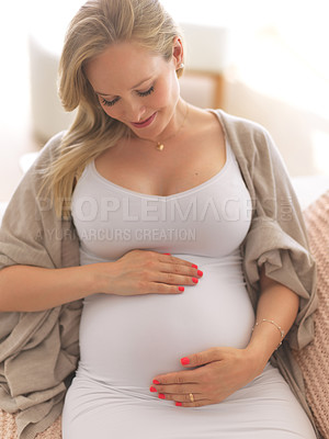 Buy stock photo High angle shot of a beautiful young pregnant woman sitting on the sofa at home