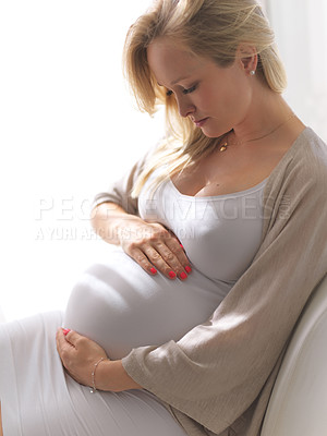 Buy stock photo High angle shot of a beautiful young pregnant woman sitting on the sofa at home