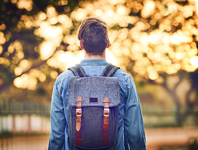 Buy stock photo Rearview shot of an unrecognizable man wearing a backpack during autumn