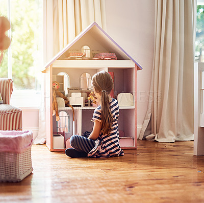 Buy stock photo Rearview shot of a little girl playing with her dollhouse while sitting on her bedroom floor