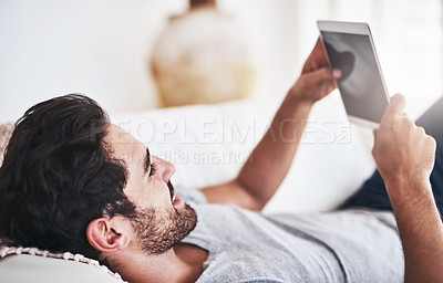 Buy stock photo Shot of a young man using wireless technology on the sofa at home