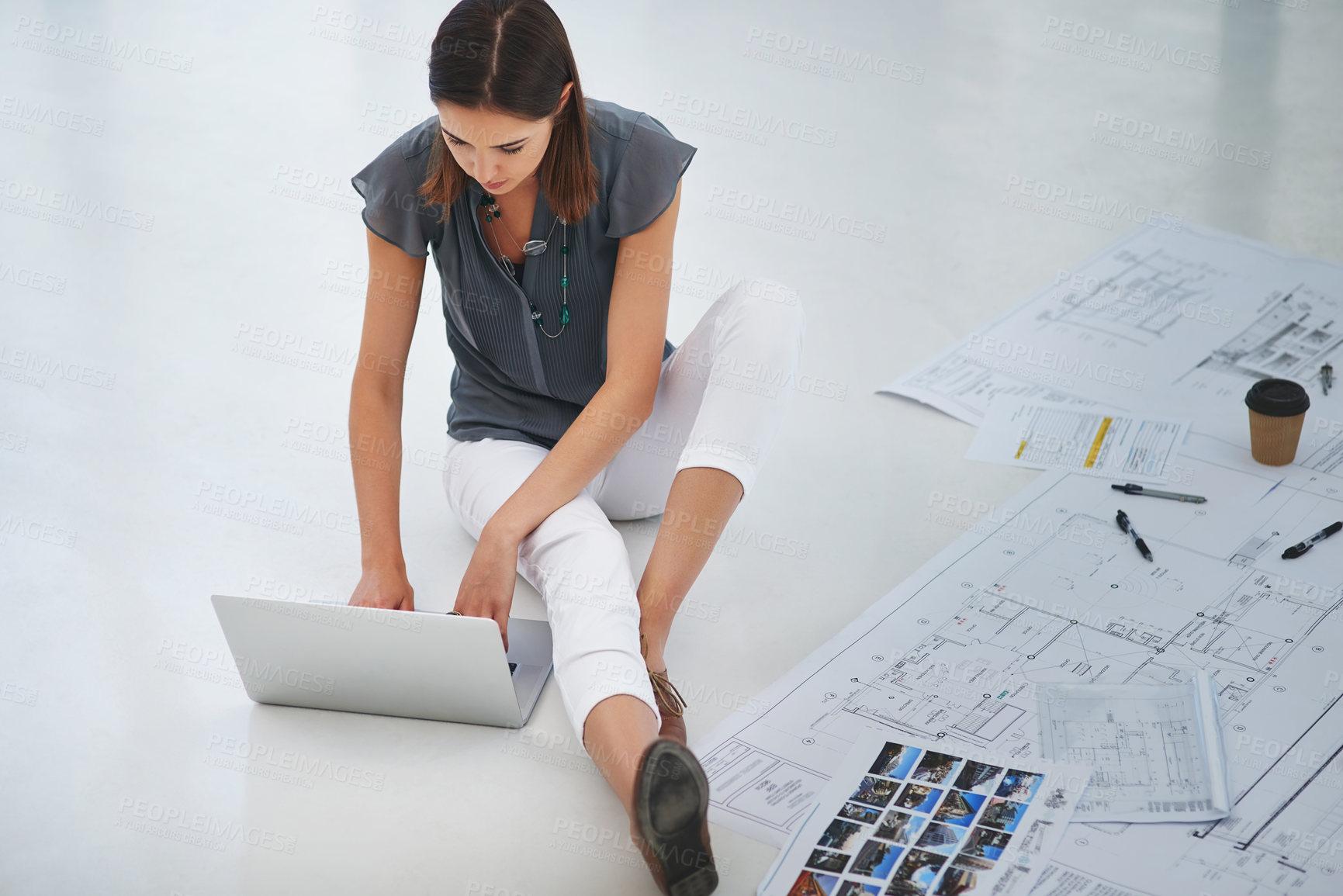 Buy stock photo Architect, woman and laptop on floor with paper, drawing and typing for research for sustainable building. Person, computer and blueprint with thinking, planning or development for property at agency