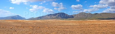 Buy stock photo Landscape of harvested farm land on a cloudy day. Empty wheat field against a blue sky. Rural agriculture with dry pasture near mountains. Wide angle of empty dirt country for copy space background.